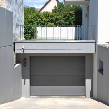 Moderne Einfahrt mit Beton-Wänden und Garage mit Automatik-Tor