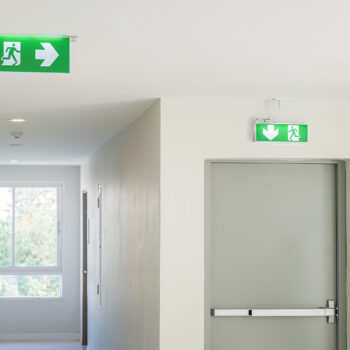 Fire exit sign with light on the path way in the hotel or office.