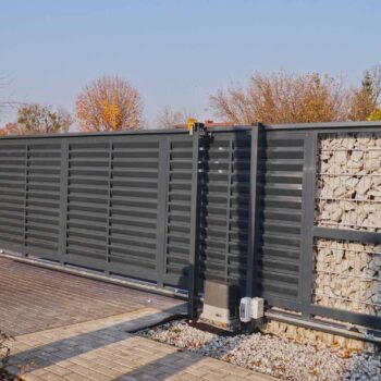 Automatic entrance gate used in combination with a wall made of gabion.